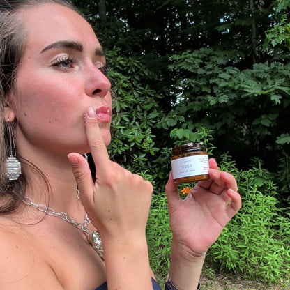 Woman applying Wyldflower Apothecary botanical lip scrub outdoors in the garden