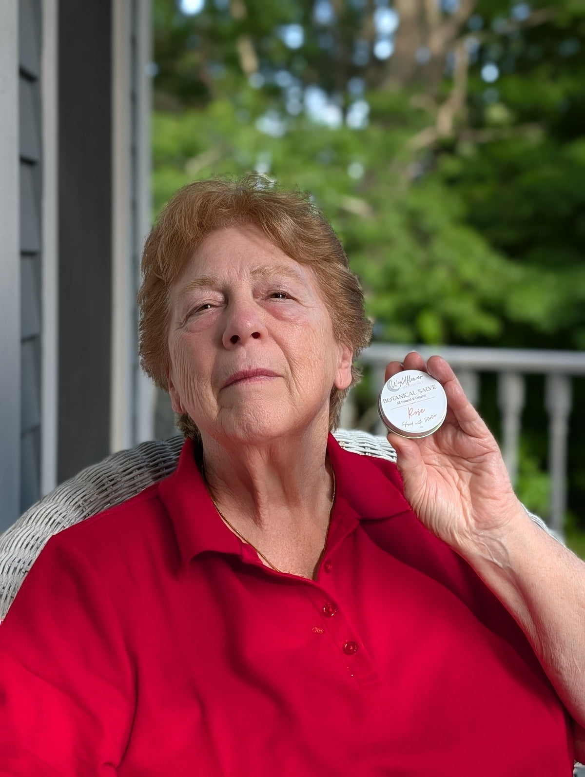 Woman holding a tin of Wyldflower Apothecary botanical salve outdoors